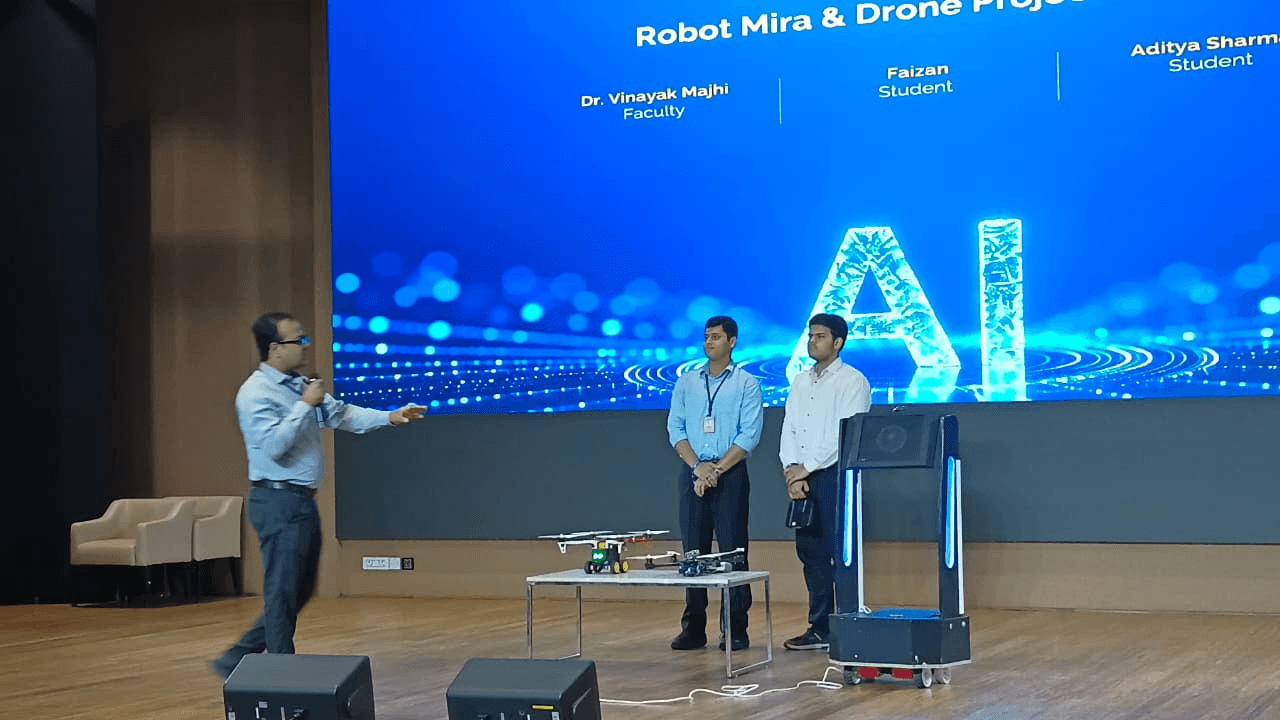 MIRA robotic assistant beside drone prototypes during an on-stage faculty and student project presentation
